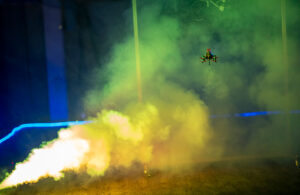 A small drone flying into fog in a dark room.