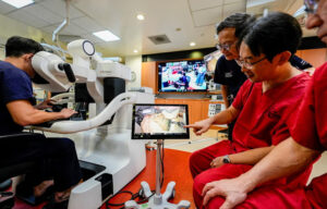 Surgeons from NUH and FHU demonstrating how the console unit in Singapore controls the four robotic arms in Nagoya, Japan.